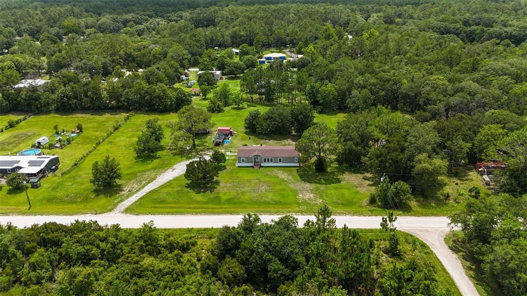 An aerial view shows a single-story house surrounded by a large grassy yard and trees — 1322 FOREST PARK STREET, BUNNELL, FL