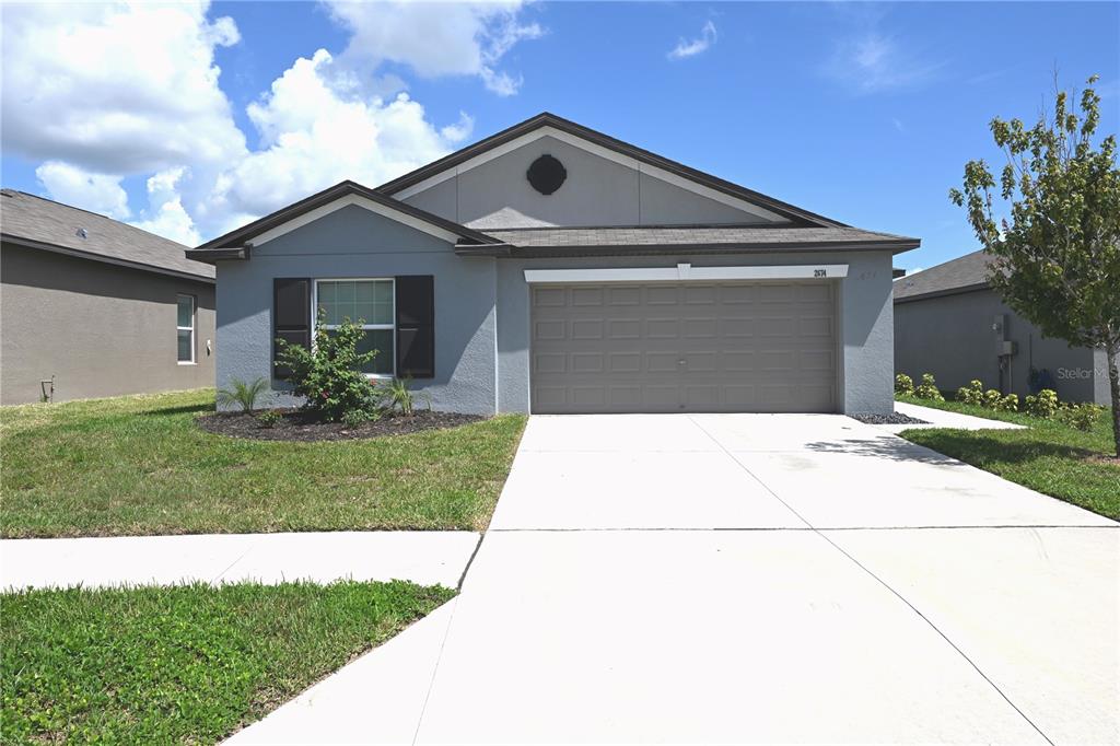 An open-concept kitchen with dark cabinets and granite countertops flows into a spacious tiled living area — 2674 RED EGRET DRIVE, BARTOW, FL