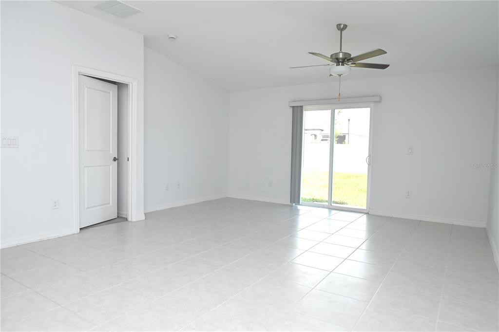 An open-concept living and dining area features light wood flooring, a ceiling fan, and furniture — 2674 RED EGRET DRIVE, BARTOW, FL