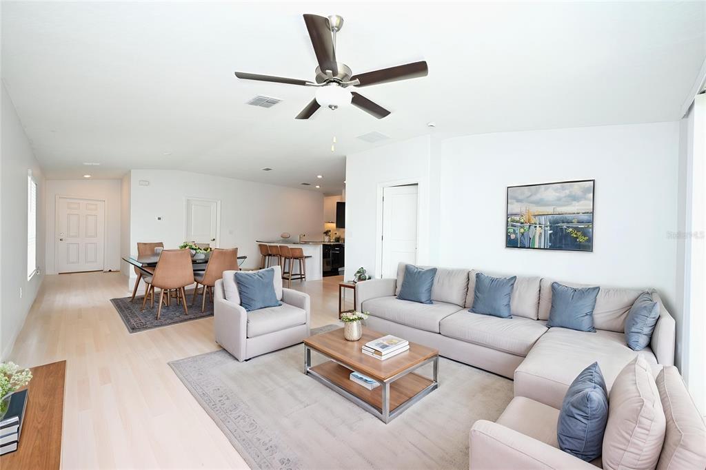A bright, open-concept living area features white tile floors, a ceiling fan, and a kitchen — 2674 RED EGRET DRIVE, BARTOW, FL