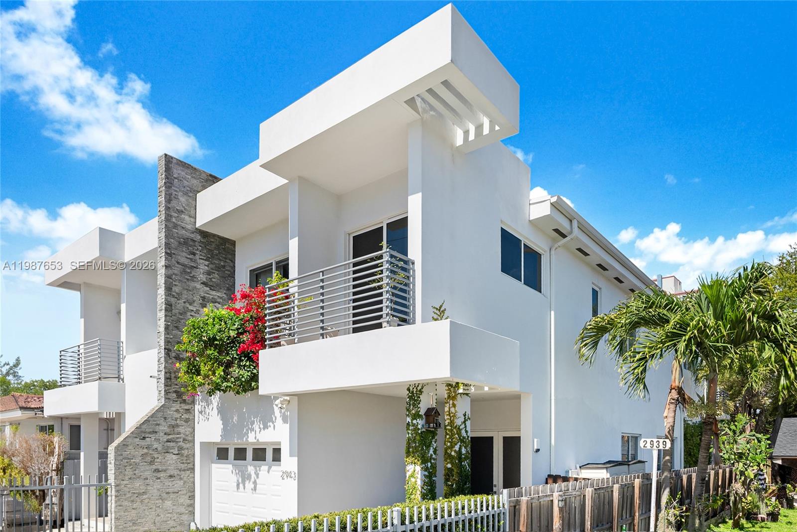 A modern two-story white house features a stone accent wall, a balcony, and a garage — 2943 SW 23rd St, Miami FL 33145, MIAMI, FL