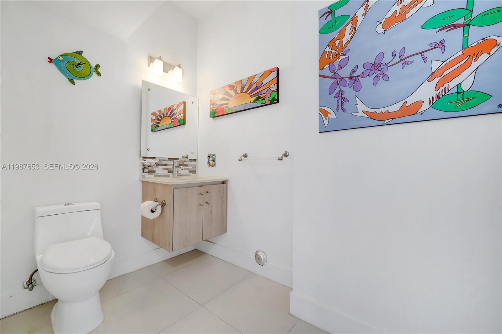 A small bathroom features a floating vanity, a white toilet, and colorful fish-themed wall art — 2943 SW 23rd St, Miami FL 33145, MIAMI, FL