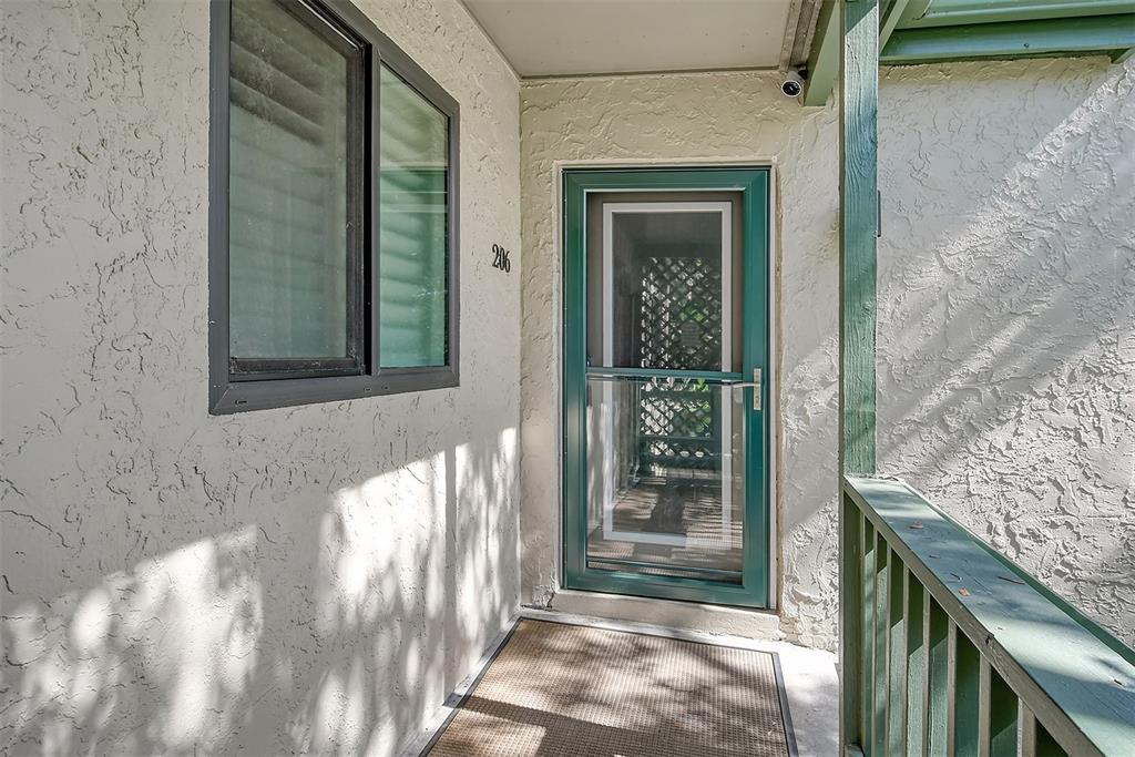 An exterior view of a residential entryway featuring a green storm door and unit number 206 — 1601 BAYHOUSE POINT DRIVE UNIT BA206, SARASOTA, FL