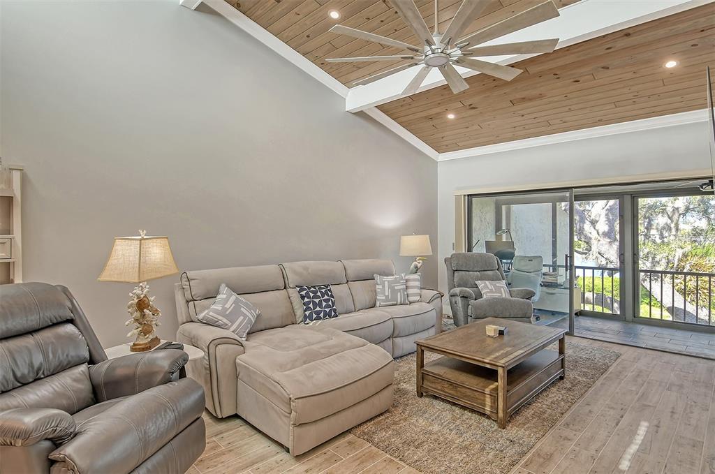 A living room features a vaulted wood-paneled ceiling, a sectional sofa, and sliding glass doors — 1601 BAYHOUSE POINT DRIVE UNIT BA206, SARASOTA, FL