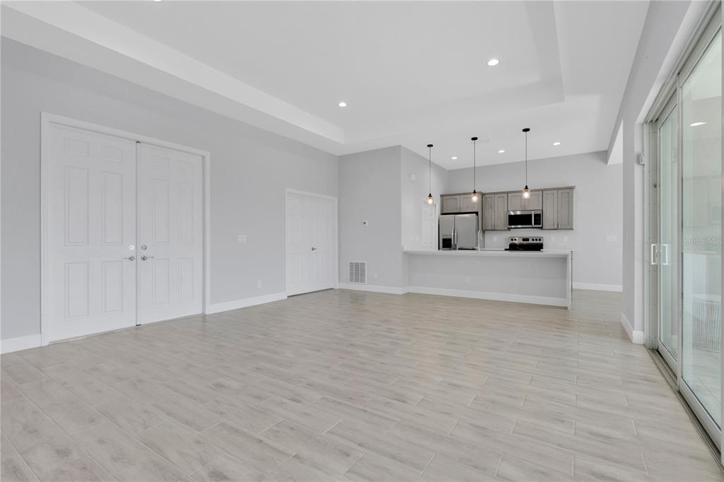 A bright, open-concept living area features light wood-look tile floors and a modern kitchen — 1306 NE 2ND AVENUE, CAPE CORAL, FL