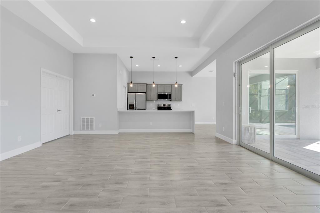 A modern kitchen with gray cabinets and an island overlooks a spacious living area — 1306 NE 2ND AVENUE, CAPE CORAL, FL