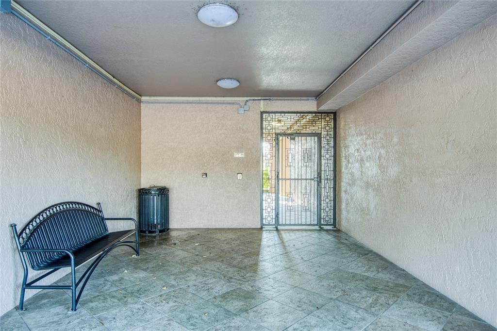 A covered entryway features a metal bench, a trash can, and a decorative security door — 6150 GULFPORT BOULEVARD S UNIT 413, GULFPORT, FL