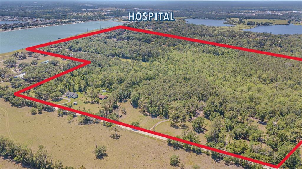 An aerial view shows a large, wooded plot of land outlined in red near a lake — 8529 KENTON ROAD, WESLEY CHAPEL, FL