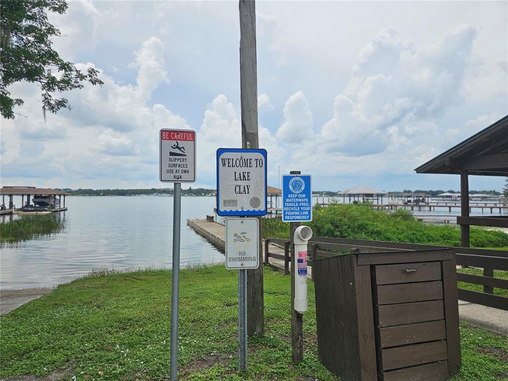 A wooden post displays several signs, including a welcome sign for Lake Clay, near a dock — 1719 CIRCLE DRIVE, LAKE PLACID, FL
