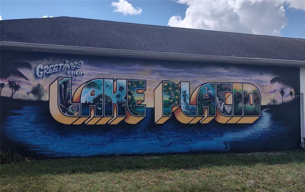 A large mural on the side of a building depicts a sunset over Lake Placid — 1719 CIRCLE DRIVE, LAKE PLACID, FL