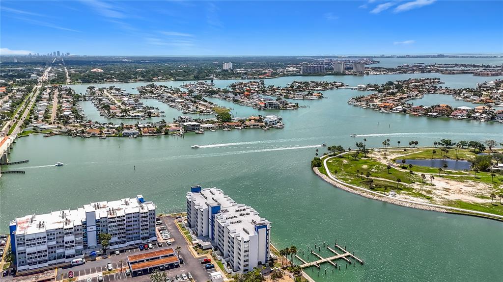 An aerial view shows two large apartment buildings near a waterway with residential islands — 450 TREASURE ISLAND CAUSEWAY UNIT 111, TREASURE ISLAND, FL