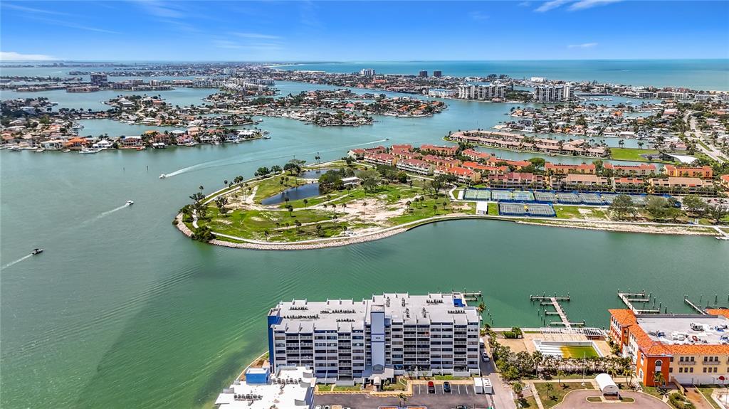 An aerial view shows a waterfront condominium building, a park, and surrounding residential islands — 450 TREASURE ISLAND CAUSEWAY UNIT 111, TREASURE ISLAND, FL