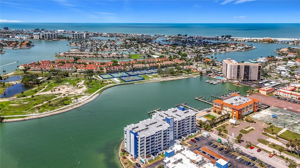 An aerial view shows a waterfront residential complex with a large pool and boat docks — 450 TREASURE ISLAND CAUSEWAY UNIT 111, TREASURE ISLAND, FL