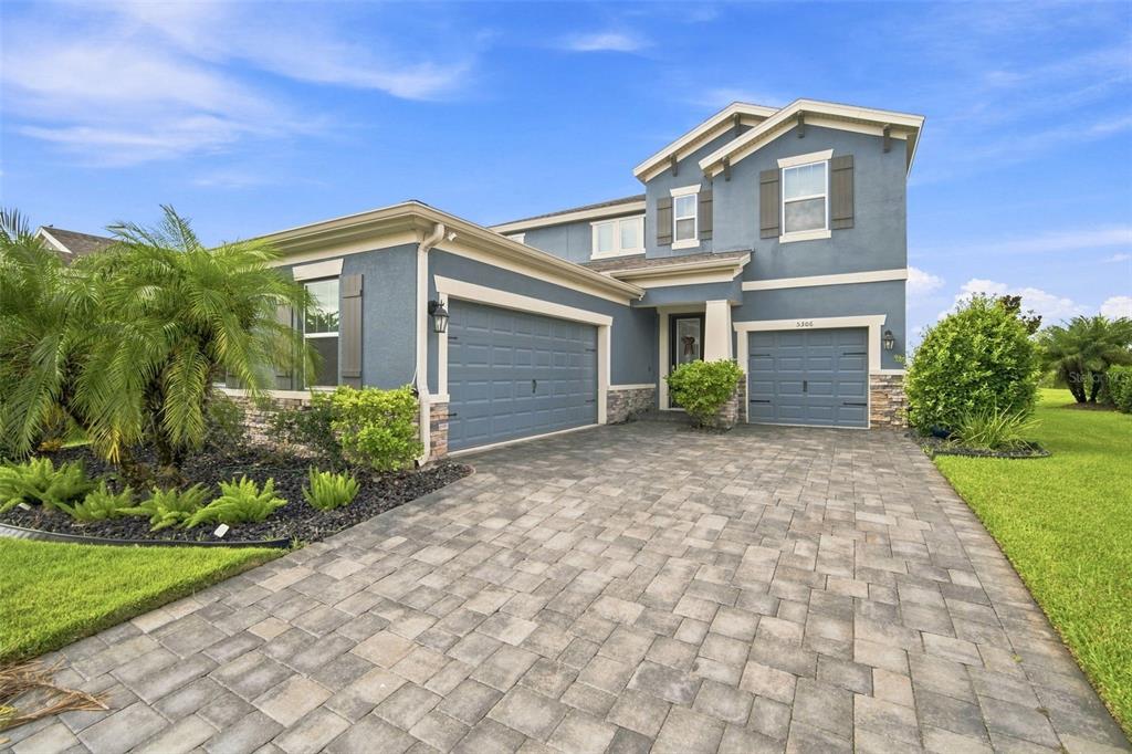 A two-story blue house with a paver driveway, two garage doors, and a palm tree — 5306 SILVER SUN DRIVE, APOLLO BEACH, FL