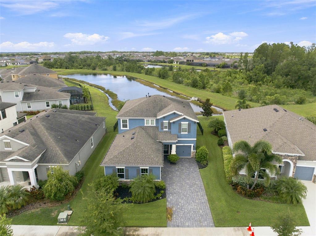An aerial view shows a blue two-story house with a paved driveway near a pond — 5306 SILVER SUN DRIVE, APOLLO BEACH, FL