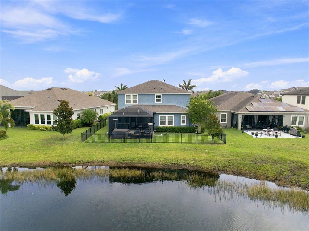 An aerial view shows a two-story blue house with a screened patio beside a pond — 5306 SILVER SUN DRIVE, APOLLO BEACH, FL
