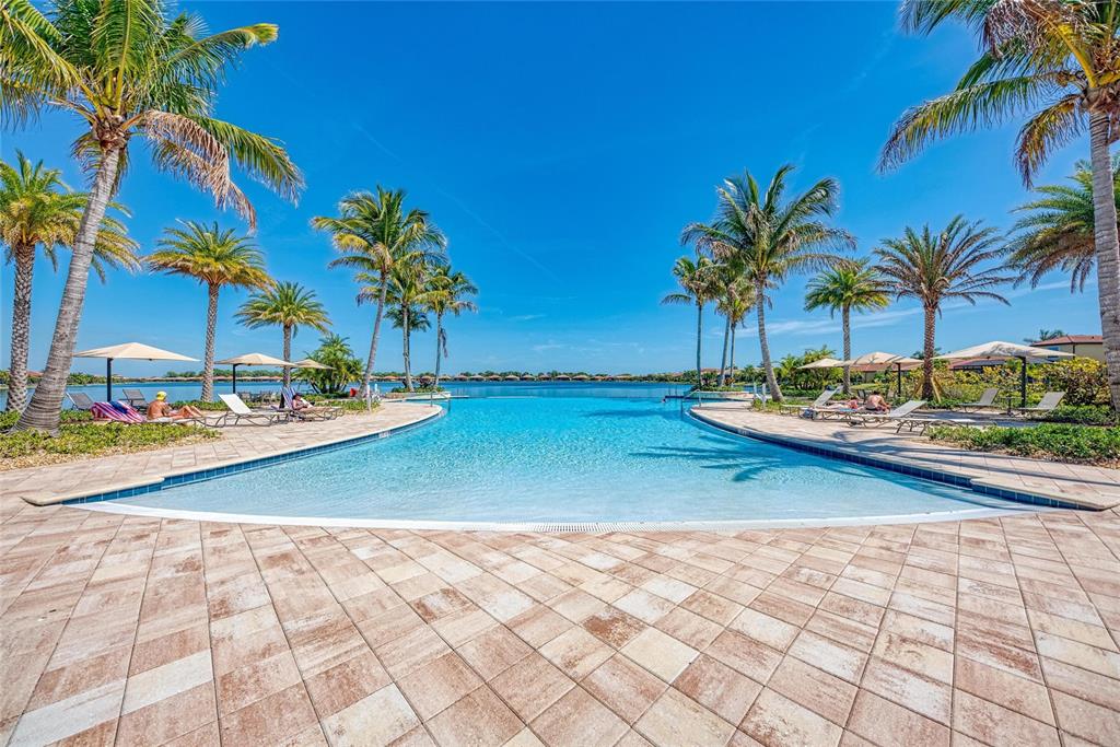 A swimming pool with lounge chairs and palm trees overlooks a large lake — 564 MARAVIYA BOULEVARD, NOKOMIS, FL