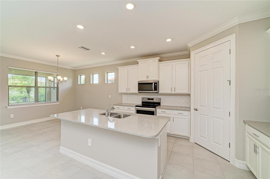 A modern kitchen features white cabinetry, a central island with a sink, and tile flooring — 564 MARAVIYA BOULEVARD, NOKOMIS, FL
