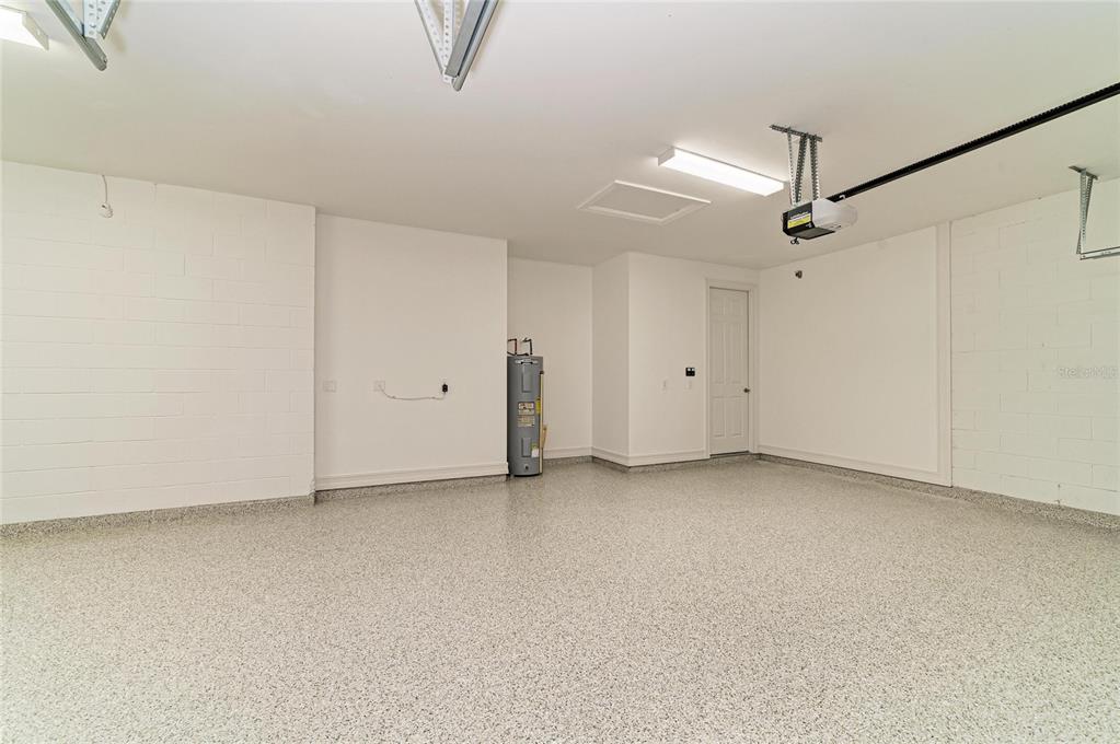 An empty garage with white block walls, a speckled epoxy floor, and a water heater — 564 MARAVIYA BOULEVARD, NOKOMIS, FL