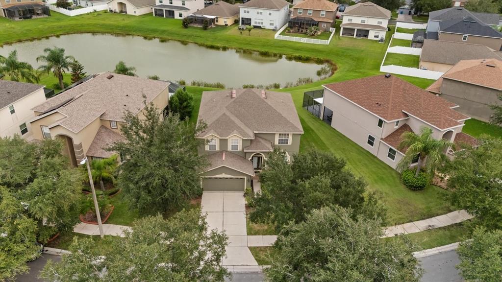 An aerial view shows a two-story suburban house with a driveway and a backyard pond — 10616 LIBERTY BELL DRIVE, TAMPA, FL