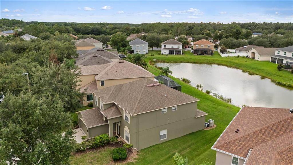 An aerial view shows a two-story house with a brown roof beside a pond — 10616 LIBERTY BELL DRIVE, TAMPA, FL