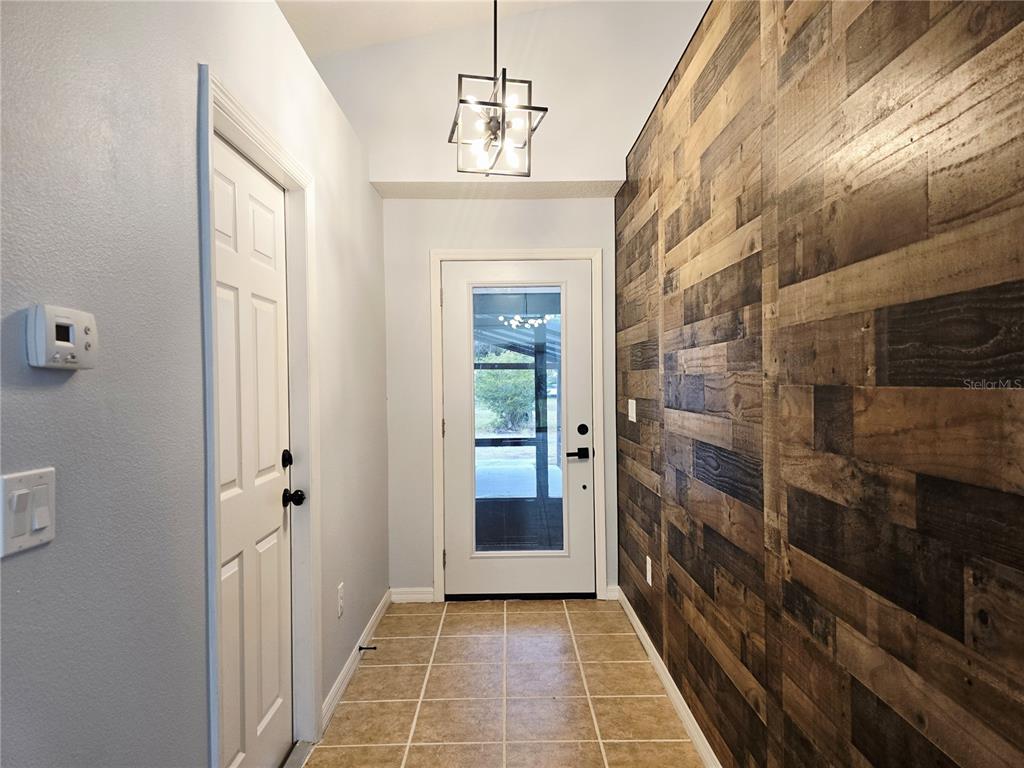 An entryway features a wood-paneled accent wall, tile flooring, and a glass-paneled front door — 531 1ST AVENUE, ALTAMONTE SPRINGS, FL