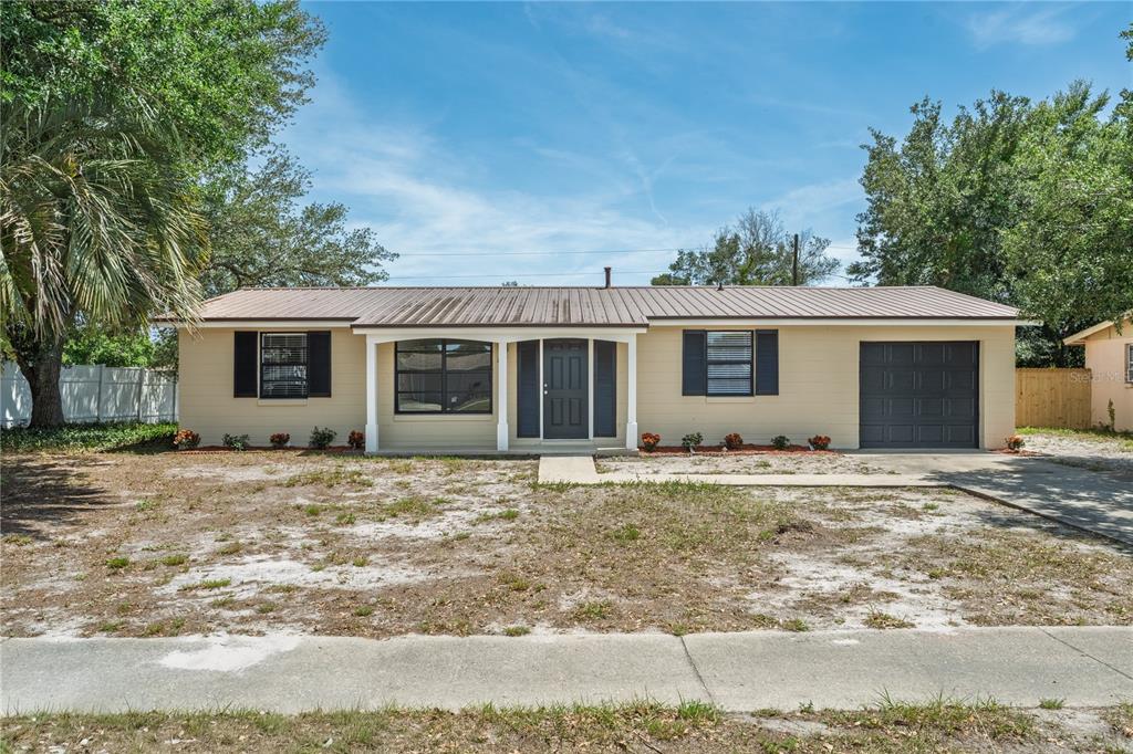 A single-story house with a metal roof, tan siding, and a one-car garage — 2919 KEESLER STREET, DELTONA, FL