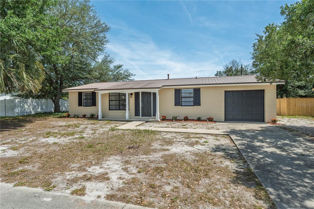 A single-story house with a tan exterior, metal roof, and an attached one-car garage — 2919 KEESLER STREET, DELTONA, FL