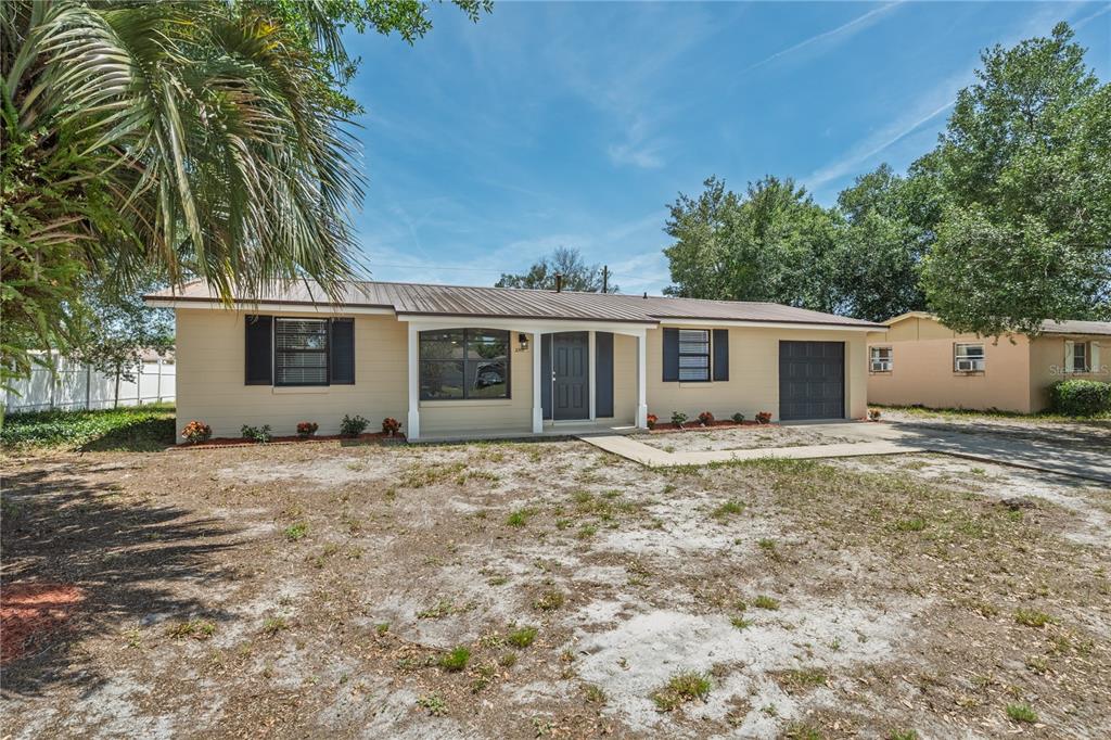 A single-story house with tan siding, a metal roof, and a small attached garage — 2919 KEESLER STREET, DELTONA, FL