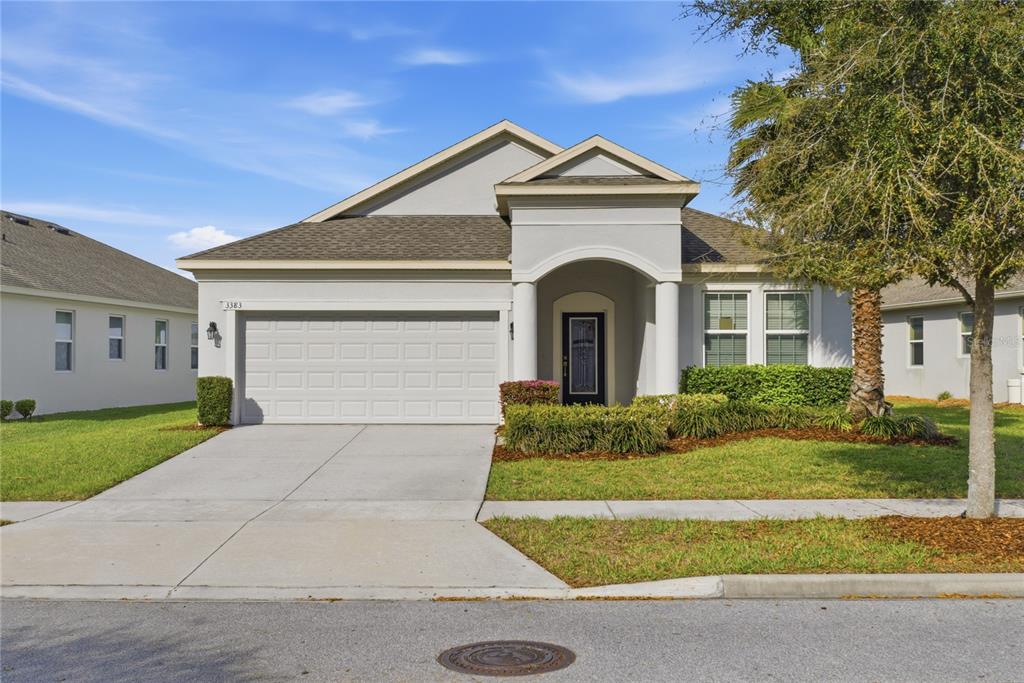 A single-story house with a two-car garage, stucco exterior, and a covered front entryway — 3383 SAGEBRUSH STREET, HARMONY, FL