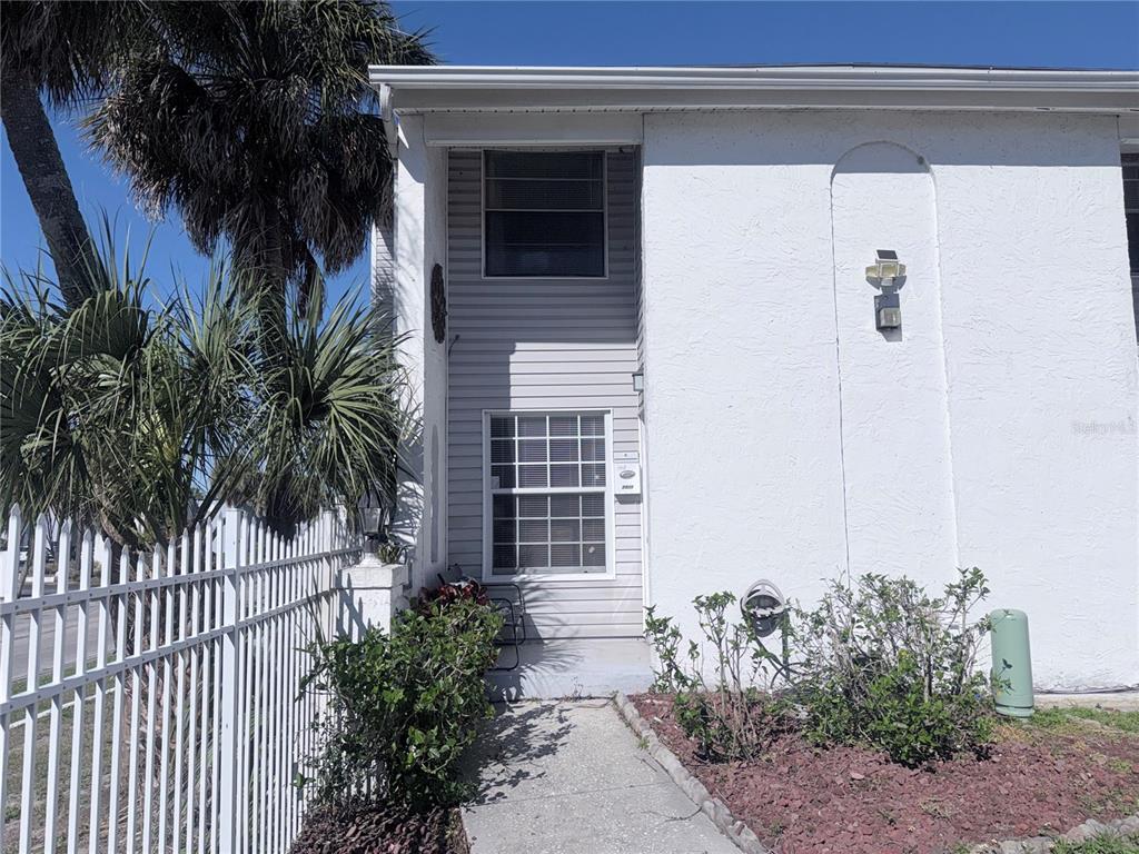 A two-story townhouse exterior features a white stucco facade, gray siding, and a front walkway — 7321 JACKSON SPRINGS ROAD, TAMPA, FL