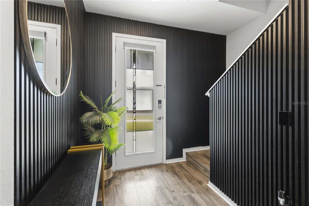 An entryway features black vertical slat walls, a white front door, and wood-look flooring — 4519 LIONS GATE AVENUE, CLERMONT, FL
