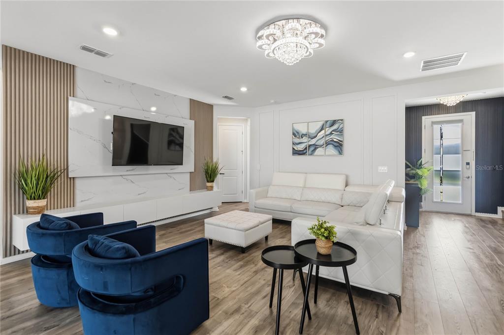 A modern living room features a marble accent wall, blue armchairs, and a white sofa — 4519 LIONS GATE AVENUE, CLERMONT, FL