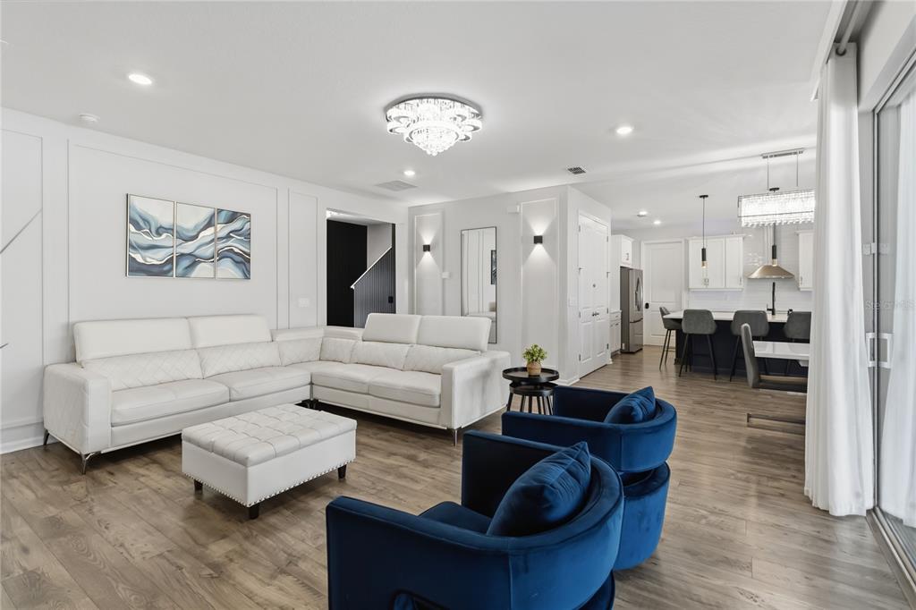 A living room with a white sectional, blue velvet chairs, and an open kitchen — 4519 LIONS GATE AVENUE, CLERMONT, FL