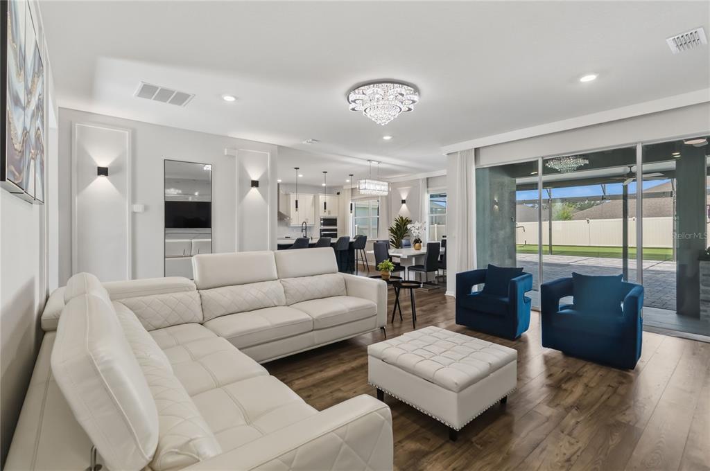 A living room with a white sectional, blue armchairs, and a view of the patio — 4519 LIONS GATE AVENUE, CLERMONT, FL
