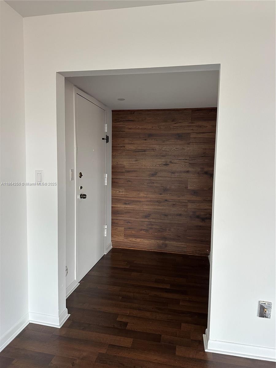 An entryway features dark wood flooring and a wood-paneled accent wall — 66 Valencia Ave, Coral Gables FL 33134, CORAL GABLES, FL