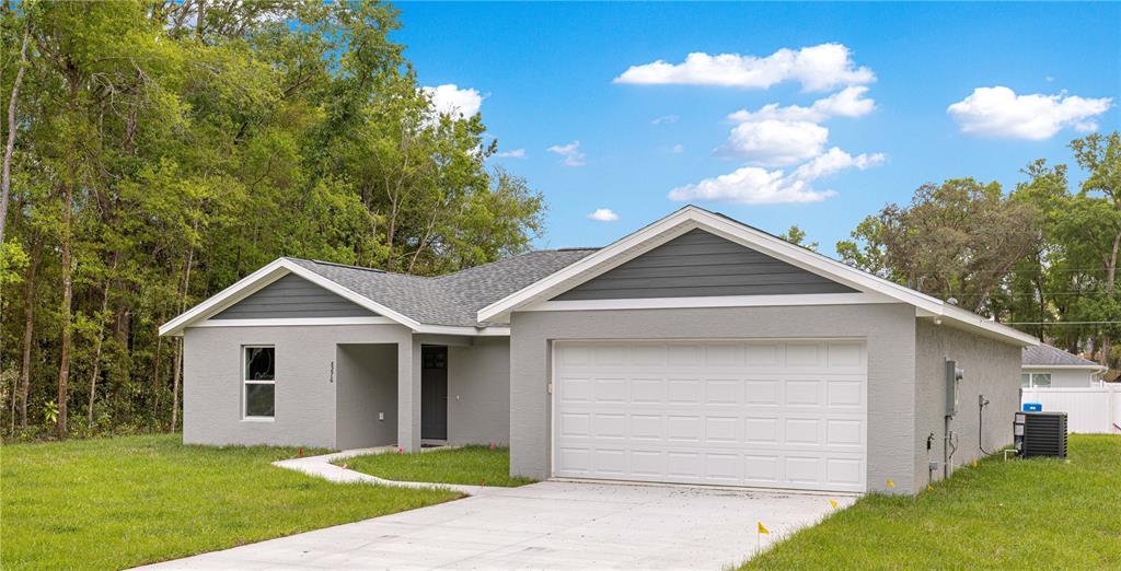 A single-story gray house with a two-car garage and a concrete driveway — 8276 SE 158TH STREET, SUMMERFIELD, FL