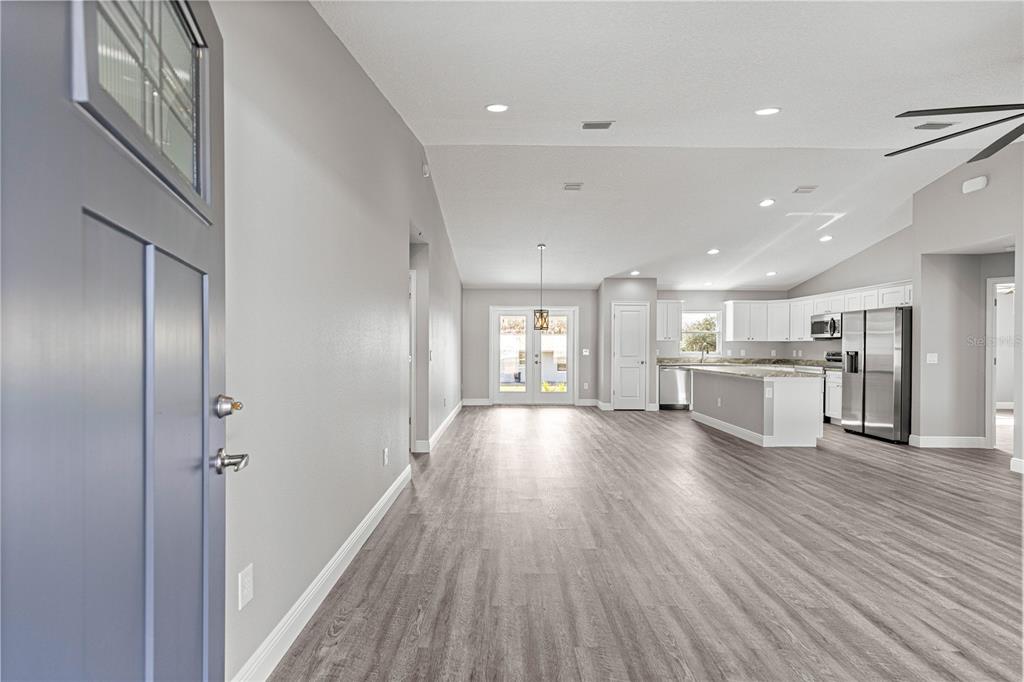 An open-concept living area features light gray walls, wood-look flooring, and a modern kitchen — 8276 SE 158TH STREET, SUMMERFIELD, FL