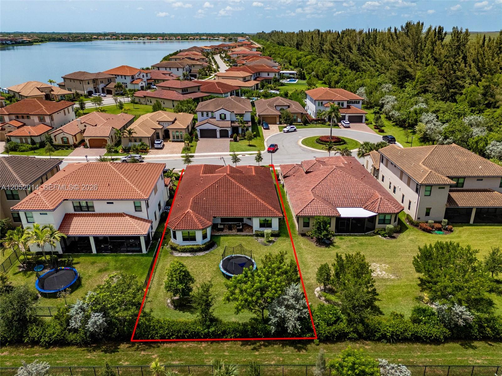 An aerial view shows a residential house with a red-tiled roof and a fenced backyard — 12835 Bayside Ct, Parkland FL 33076, PARKLAND, FL