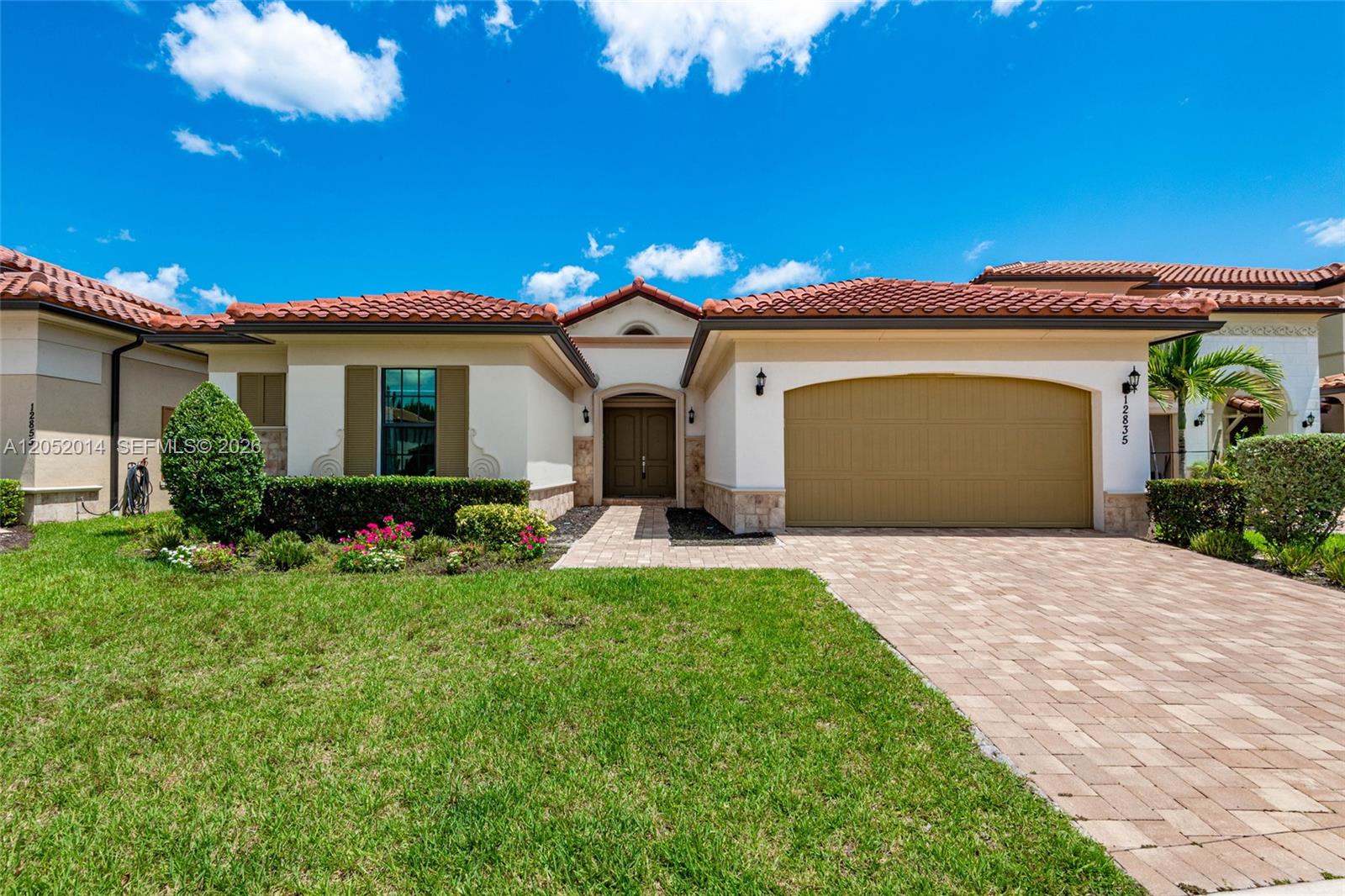 A single-story house features a tiled roof, a paved driveway, and a two-car garage — 12835 Bayside Ct, Parkland FL 33076, PARKLAND, FL