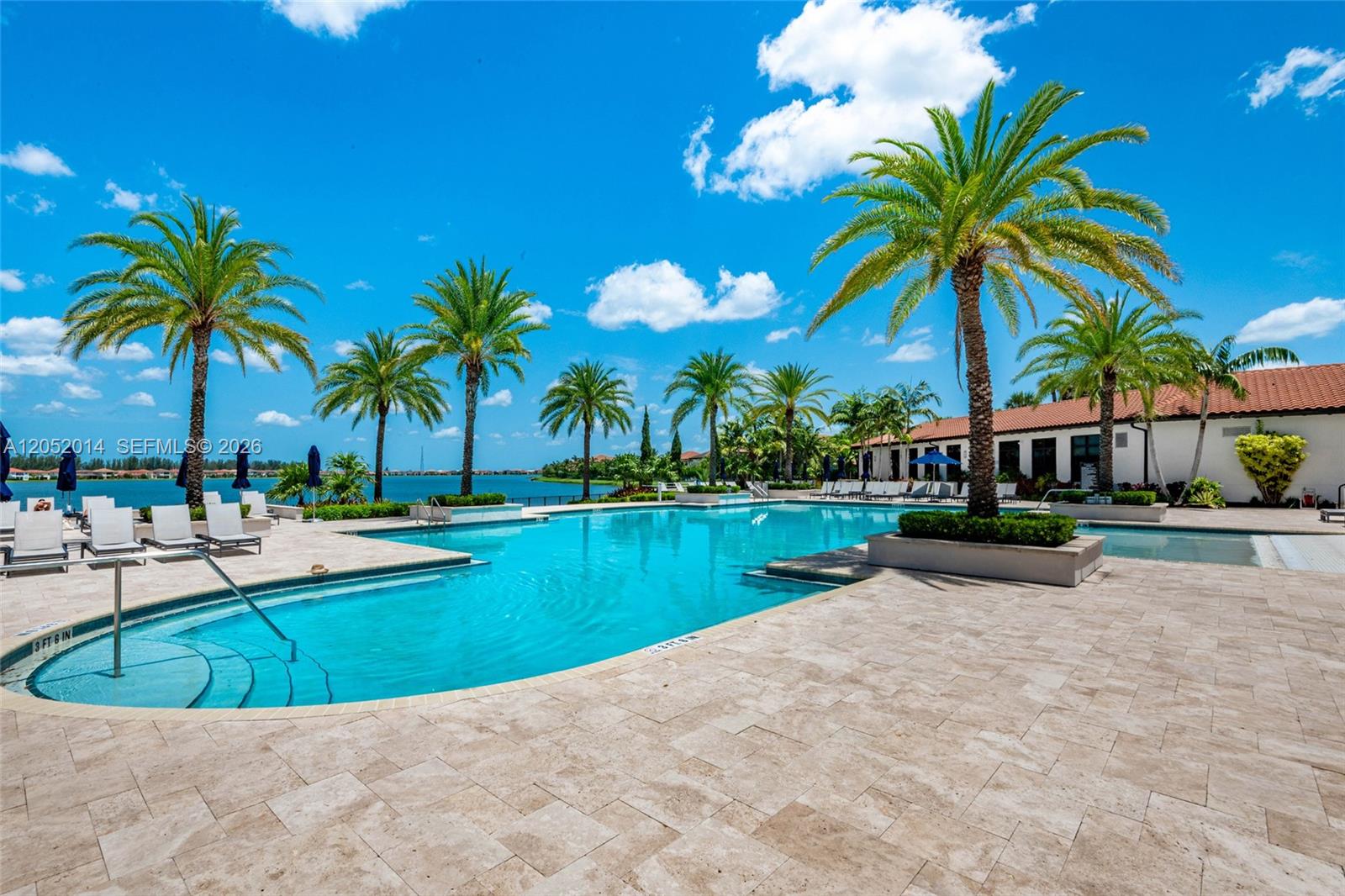 A swimming pool with lounge chairs and palm trees overlooks a large body of water — 12835 Bayside Ct, Parkland FL 33076, PARKLAND, FL