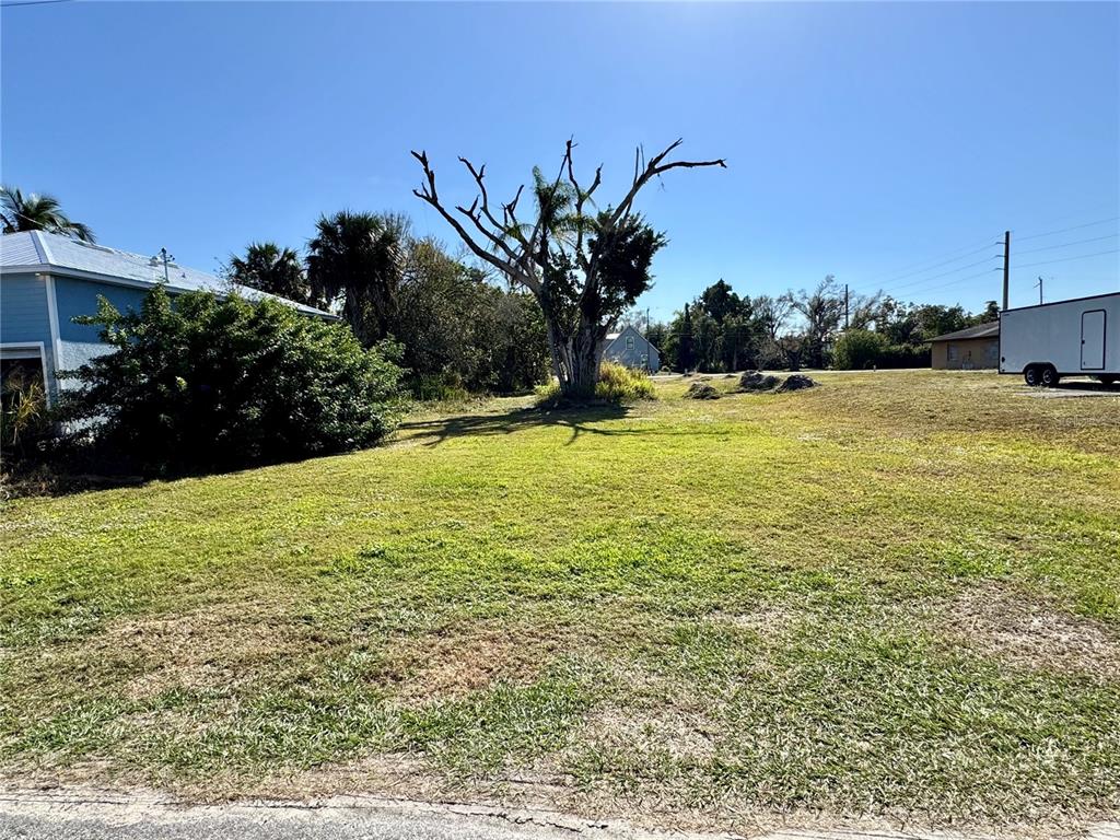 A grassy, vacant residential lot features a large, bare tree and a neighboring house — 623 FITZHUGH AVENUE, PUNTA GORDA, FL