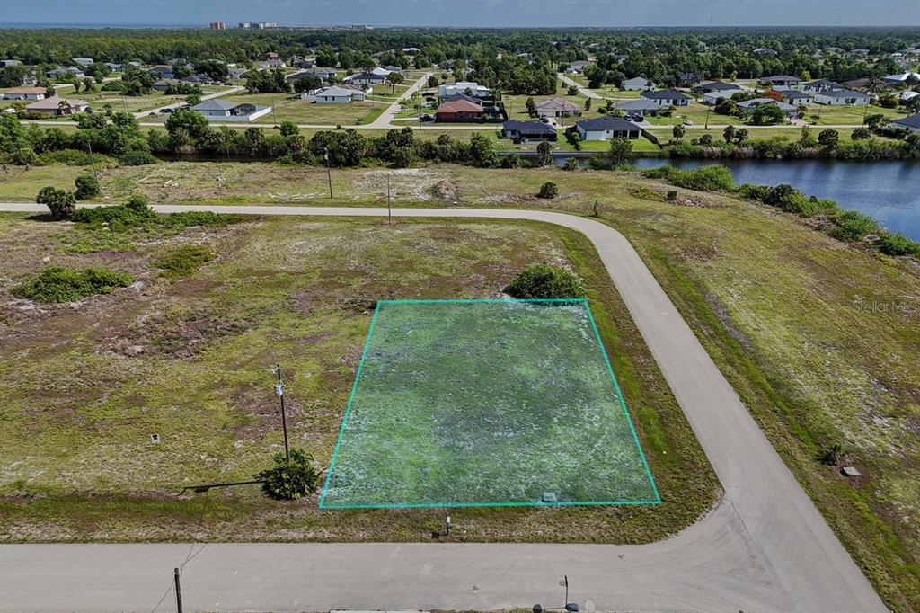 An aerial view shows a vacant, rectangular residential lot outlined in green near a canal — 3801 NW 41ST STREET, CAPE CORAL, FL