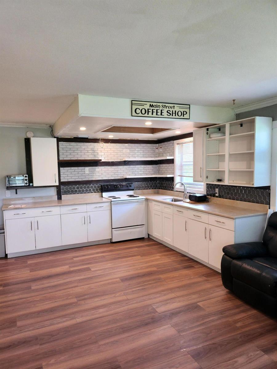 A kitchen with white cabinets, wood-look flooring, open shelving, and a coffee shop sign — 168 Durham # 168, Deerfield Beach FL 33442, DEERFIELD BEACH, FL