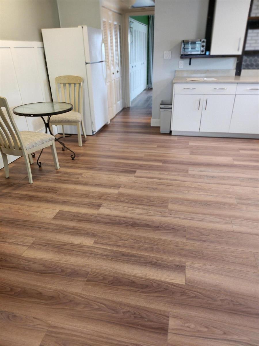 A kitchen and dining area featuring wood-look flooring, white cabinets, and a small bistro set — 168 Durham # 168, Deerfield Beach FL 33442, DEERFIELD BEACH, FL