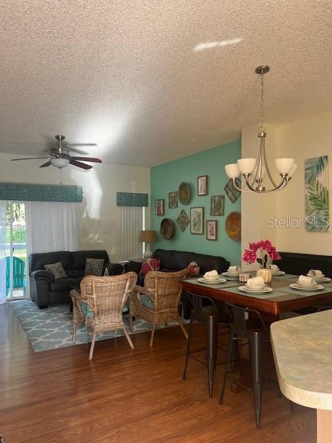 An open-concept living and dining area features wood flooring, a teal accent wall, and wicker furniture — 8405 CRYSTAL COVE LOOP, KISSIMMEE, FL