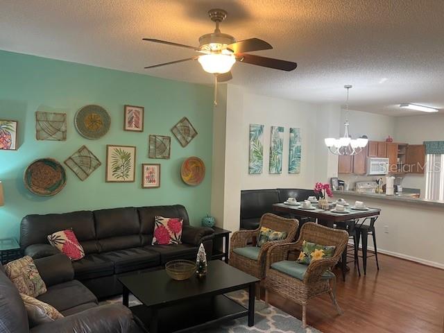 A living room with a teal accent wall, dark leather sofa, and adjacent dining area — 8405 CRYSTAL COVE LOOP, KISSIMMEE, FL