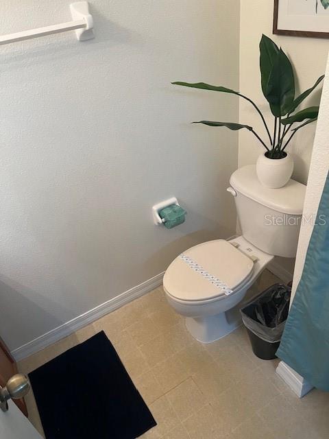 A bathroom features a white toilet, a potted plant, and a black floor mat — 8405 CRYSTAL COVE LOOP, KISSIMMEE, FL