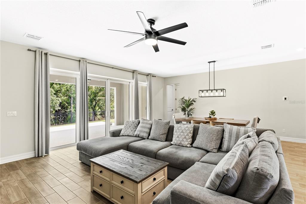 A living room features a gray sectional sofa, a wooden coffee table, and sliding glass doors — 6035 BLUE VIEW WAY, ST CLOUD, FL