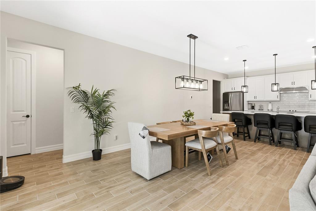 A dining area with a wooden table and chairs sits adjacent to a modern kitchen — 6035 BLUE VIEW WAY, ST CLOUD, FL